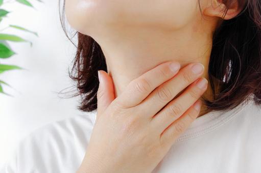 喉をおさえている女性